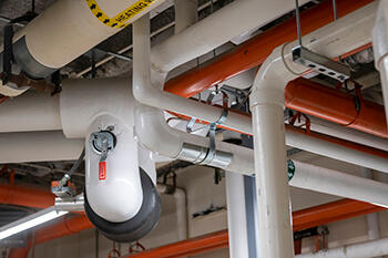View of piping and mechanical equipment running along a ceiling